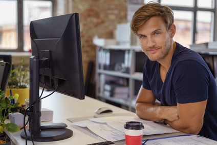 zufriedener junger mitarbeiter arbeitet am computer