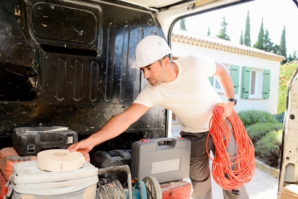 young electrician artisan taking tools out of professional truck van